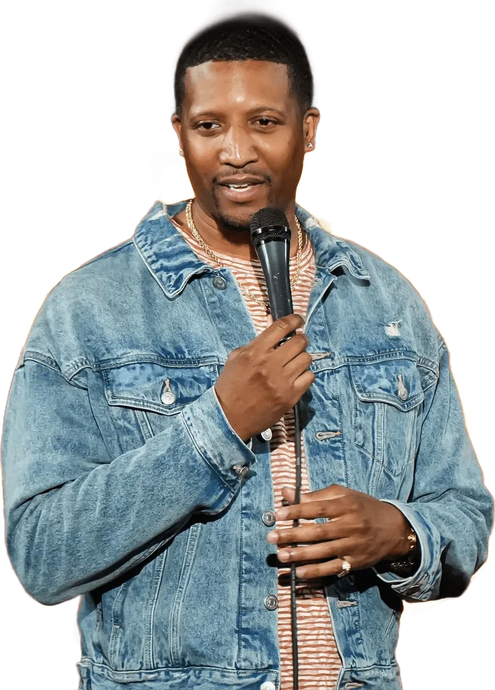 Jae doing stand-up in a denim jacket, mic in hand